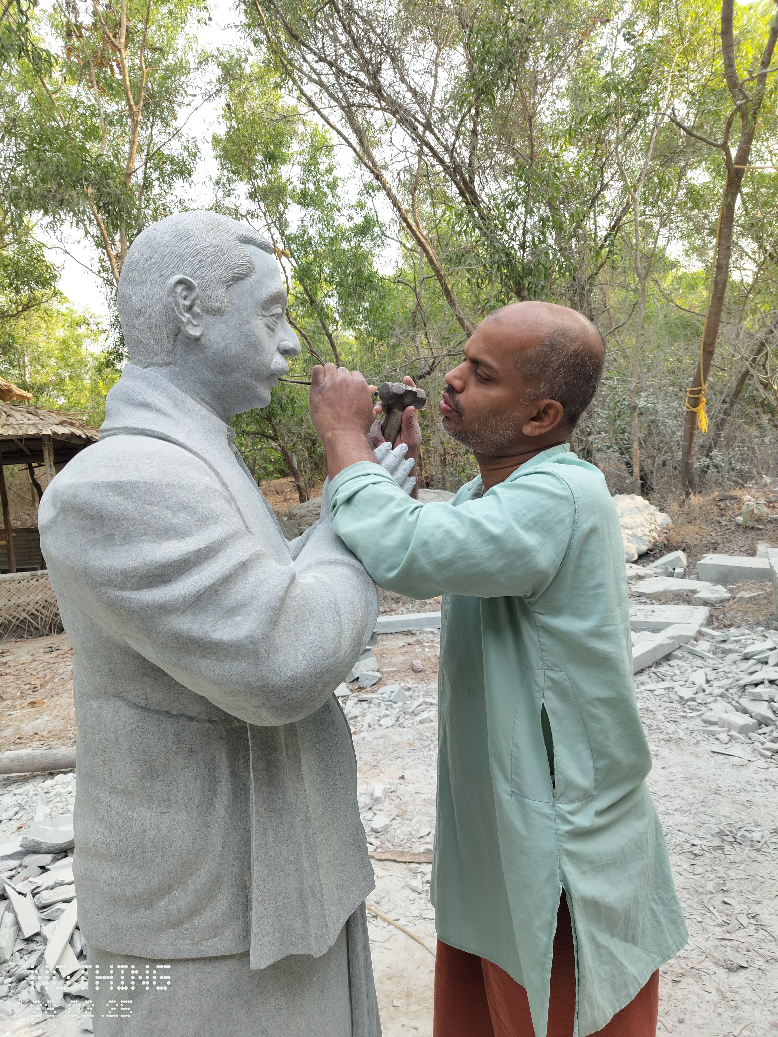 Sri Chidananda Acharya carving a photorealistic stone portrait of a public figure